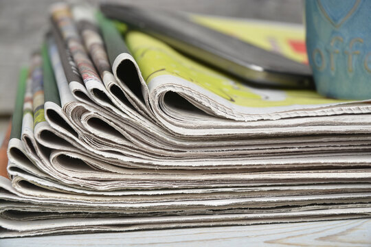 Stacked and piled up newspapers on a wooden table background
