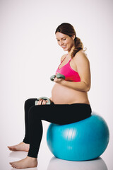 Fototapeta na wymiar Young pregnant woman excercises with gymnastic ball