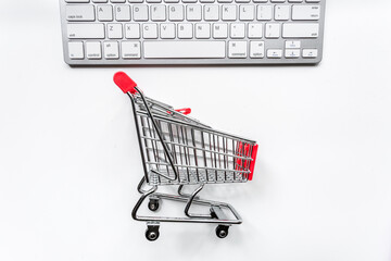 buying products with keyboard and mini trolley on dark table background top view