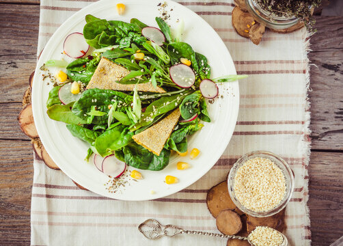 Salad with baby spinach, corn, radish, sesame and crispy crackers