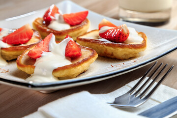 pancakes with strawberries and sour cream on a beautiful plate stand on the table