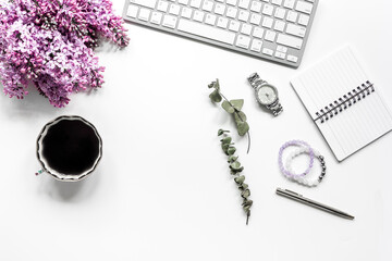 work place with lilic flowers and notebook for woman on white desk background top view mock-up