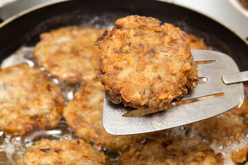 Meat patties are fried in a frying pan