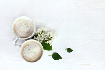  spring coffee aroma/ Flat layout with a couple of mugs cappuccino and a lilac branch on the table...