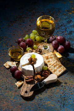 Camembert cheese, snacks and a glass of white wine, vertical