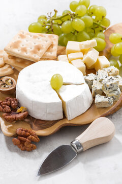 camembert, grapes and crackers on a white background, vertical, closeup