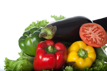 Closeup of fresh vegetables on wooden plate and white background. A composition of vegetables. Healthy eating and healthy diet. Bell peppers, carrots, tomato, eggplant, lettuce. Top view