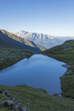 The alpine lake frames the green valley and Rifugio Bozzi, Val Di Viso, Camonica Valley, province of Brescia, Lombardy