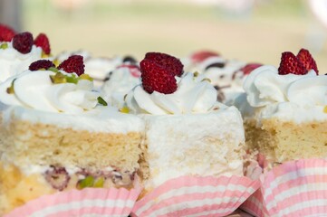 Porzioni di torta di Pan di Spagna, guarnite con panna, piostacchi e fragole