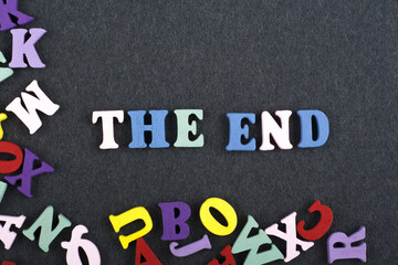 THE END word on black board background composed from colorful abc alphabet block wooden letters, copy space for ad text. Learning english concept.