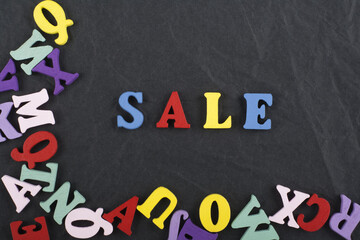 Sale word on black board background composed from colorful abc alphabet block wooden letters, copy space for ad text. Learning english concept.