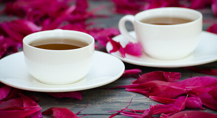 Hot tea and peony petals on dark