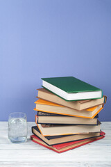 Book stacking. Open book, hardback books on wooden table and blue background. Back to school. Copy space for text.