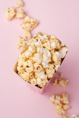 Popcorn in red and white cardboard box on the pink background.