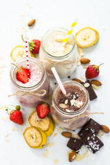 Banana chocolate and strawberry milkshakes in jars on white. Top view.