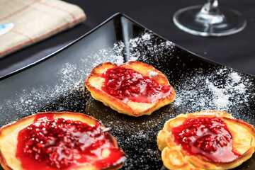 pancakes with raspberry jam on a beautiful black plate standing on the table