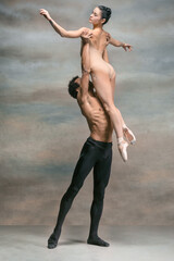 Couple of ballet dancers posing over gray background