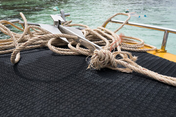 Focus on a small anchor with rope on the boat