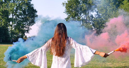 On a sunny day, a woman walks across the field with a colored smoke flare in a white dress against a nature background. Concept life style, ecology, colorful happy people freedom wonderfully beautiful