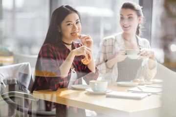 young girls eating croissants and drinking coffee at cafe, coffee break