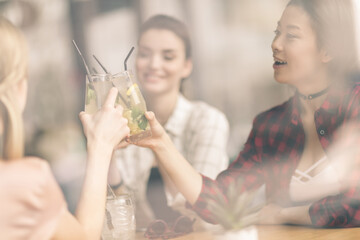 young girls drinking cocktails together while sitting at table in cafe, having lunch