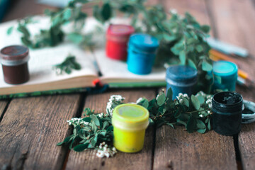 Jar of paint on a wooden background with leaves of plants.