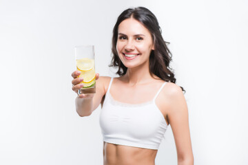 smiling woman showing glass of water with lemon isolated on white