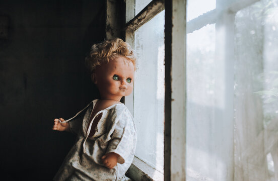 The old doll looks out the window. Fear and horror.