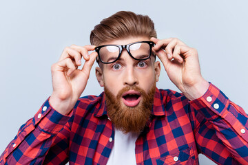 It's incredible! Close up portrait of young bearded man touching the spectacles and keeping his...