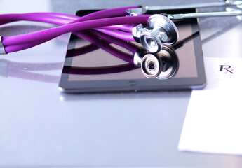 Tablet computer with a stethoscope lie on a table