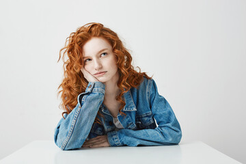 Naklejka premium Dreamy beautiful girl thinking dreaming sitting at table over white background.