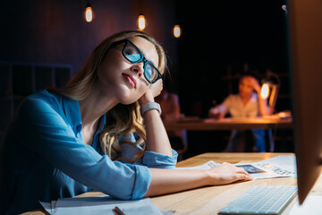 Exhausted young businesswoman in eyeglasses sleeping at workplace