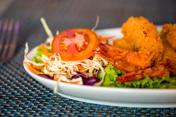 Large shrimp in batter with vegetables on a plate close up