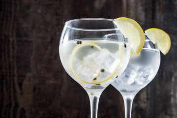 Glass of gin tonic with lemon on wooden background
