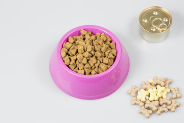 Dog biscuits in pink plastic bowl on white background