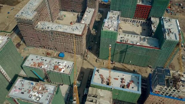 Aerial shot of big construction site. Rooftops of unfinished modern apartment buildings. 4K video