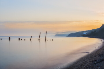 Sea landscape, the sea at sunset, twilight, long exposure. Calm sea. Beautiful beach. Silhouettes of hills on the shore in the haze in the distance.
