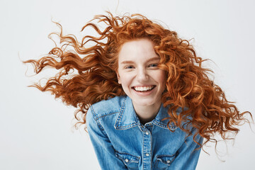 Portrait of beautiful cheerful redhead girl with flying curly hair smiling laughing looking at...