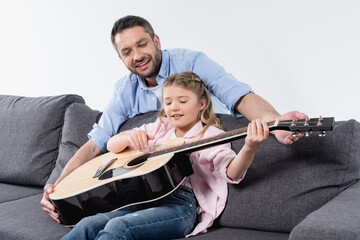Fototapeta premium smiling father teaching his adorable daughter to play on guitar