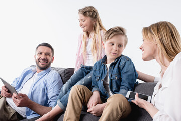 caucasian family with digital devices sitting on sofa together