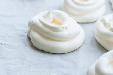 Preparation for garnishing homemade individual meringue cakes Pavlova on white parchment paper