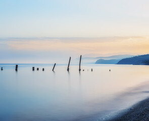 Sea landscape, the sea at sunset, twilight, long exposure. Calm sea. Beautiful beach. Silhouettes of hills on the shore in the haze in the distance.
