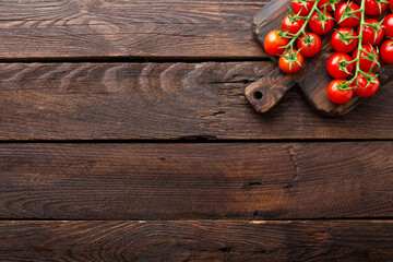 Naklejka premium Fresh cherry tomatoes on twigs on wooden table, top view