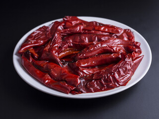 Grilled red peppers with salt, pepper and olive oil placed on white plate and isolated on black background