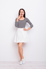 Full size portrait of cute playful girl. She is wearing casual clothes and stands on pure white background, amazed