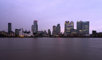 business part of london in uk canary wharf at dusk behind river thames