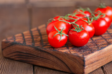 Fresh raw cherry tomatoes on a wooden board with pepper garlic. Wooden background. Close up and copy space.