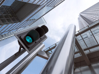 modern high rise buildings with reflections of blue sky and clouds with green traffic light