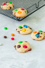 Cookies with colorful candies and chocolate chips on a white stone background.