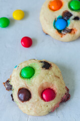 Cookies with colorful candies and chocolate chips on a white stone background.